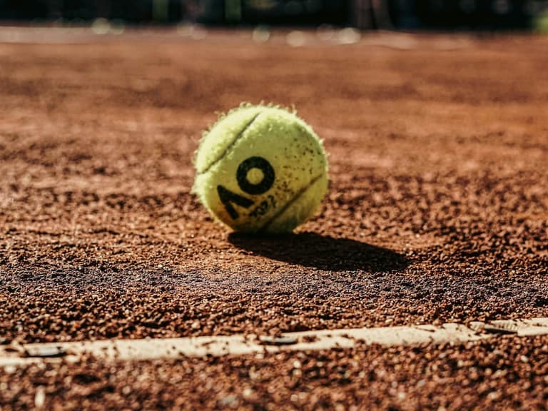 A tennis ball on a clay court.