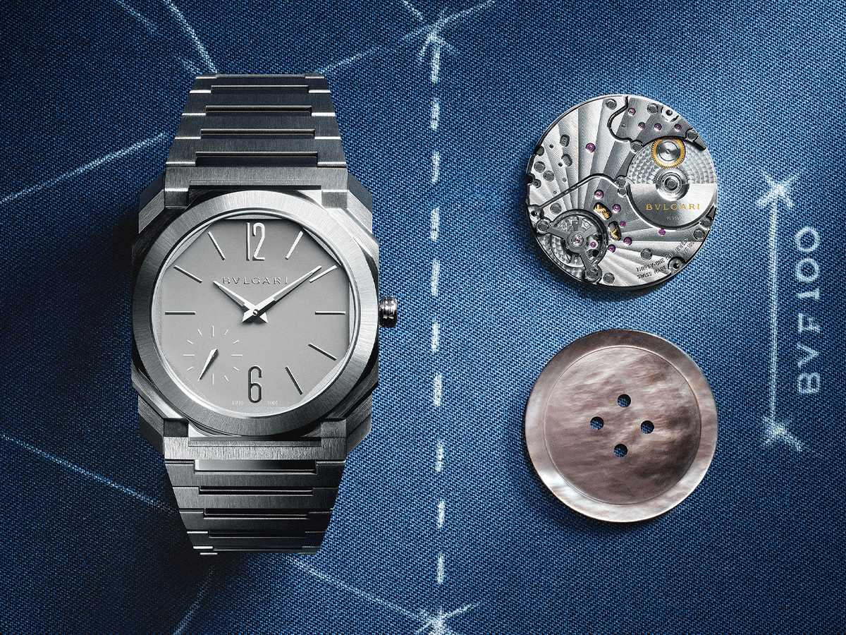 Bulgari Octo Finissimo watch in silver with exposed movement and dial components on a blue textured background.