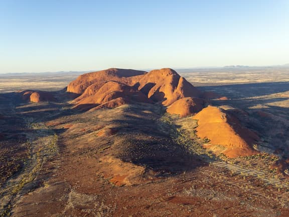 Uluru at sunrise, a red monolith rising from the Central Australian desert