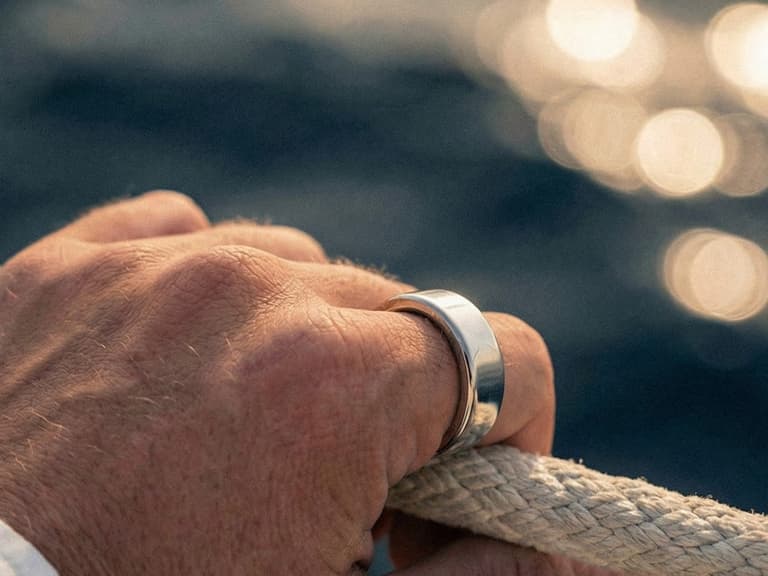 Ultrahuman Ring PRO worn on a hand gripping a rope over open water