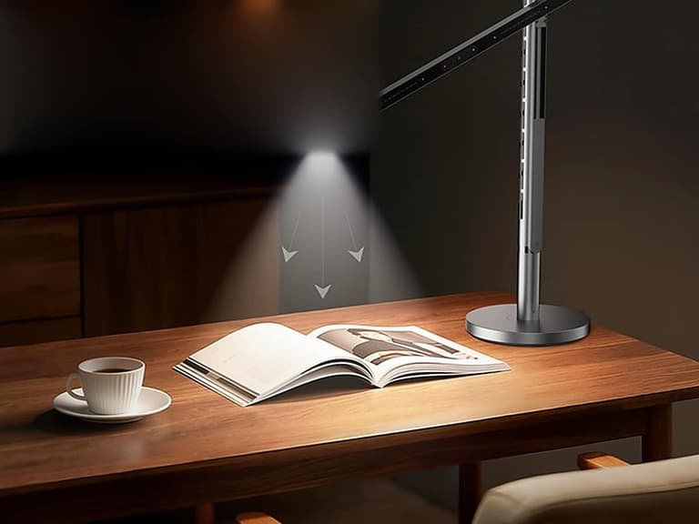 L3 Pro desk lamp casting light straight down over an open book on a timber desk beside a cup of coffee