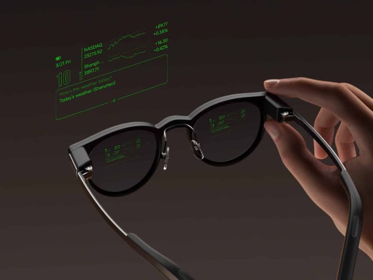 MemoMind One glasses held in one hand with green heads-up display text visible across both lenses