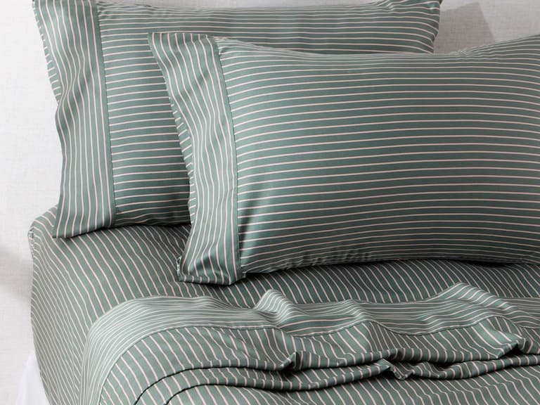 Sage green and white pinstripe 400 thread count bamboo cotton sheets and pillowcases on a made bed in soft daylight.