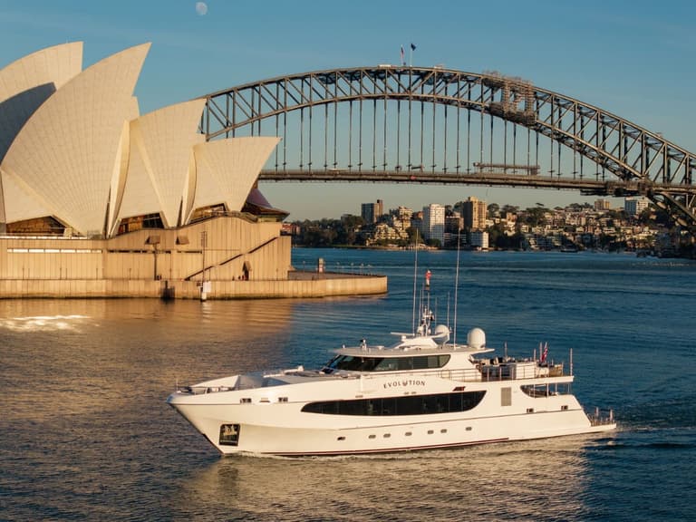 The superyacht Evolution cruising past the Sydney Opera House and Harbour Bridge