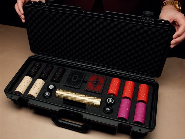 The Official John Wick Poker Set open in its black hard case, showing clay chips, gold coins and two decks of cards